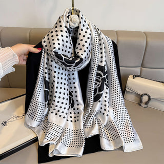 Black and white polka dot scarf with floral patterns on a beige sofa.