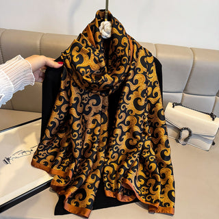 Black and gold patterned scarf held by a hand on a light-colored sofa.