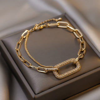 Gold chain bracelet with diamond accents on a brown jewelry box