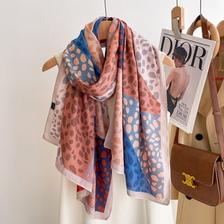 Patterned scarf on a hanger with a Dior magazine and brown handbag in the background.
