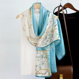 A woman's silk scarf with a floral pattern displayed on a hanger, featuring blue, white, and beige colors.