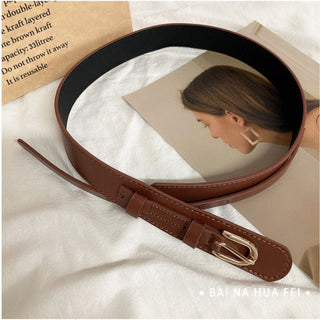 Brown leather belt with gold buckle on a magazine background