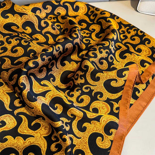Fabric with gold and black pattern on a white surface