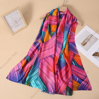 A colorful satin silk scarf with a geometric pattern, displayed on a mannequin against a backdrop featuring a picture frame and some documents.